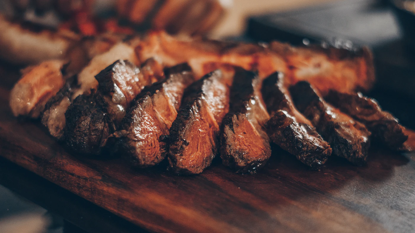 Slices of deeply seared steak on a dark wooden board — the Maillard reaction